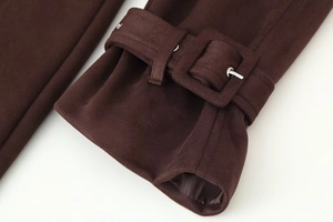 Detail of dark brown faux suede coat cuff with adjustable strap and silver buckle
