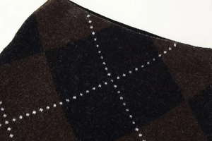 Detailed macro view of argyle knit fabric with thick brown and black geometric patterns
