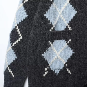Detail of argyle knit cardigan with blue and grey pattern and black resin buttons