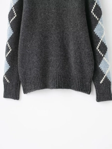 Close-up detail of argyle knit pattern and ribbed cuff on a gray wool cardigan