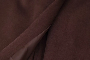 Detail shot of the heavy dark brown wool fabric and silk-like satin lining on the long coat