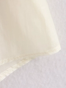 Detailed macro view of double-stitched hem on ivory lightweight embroidery shirt