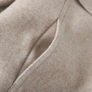 Detailed view of oatmeal beige wool jacket showing high-quality stitching and pocket