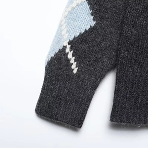 Close-up of thick knit cuffs and geometric diamond pattern on grey cardigan