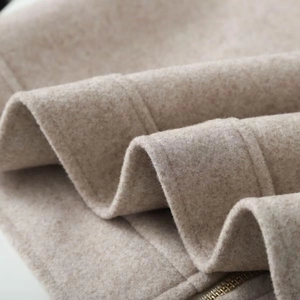 Macro shot of oatmeal-colored wool coat featuring premium metal zipper and fine stitching