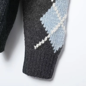 Close-up of grey argyle knit cardigan featuring blue diamond patterns and ribbed cuffs