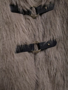 Detail of taupe faux fur coat featuring black leather strap and gold metal ring closure