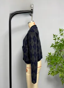 Detail view of navy blue and grey argyle knit cardigan with ribbed cuffs and side pockets