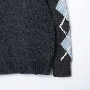 Detailed view of the dark grey knit cardigan sleeve with blue and white argyle pattern