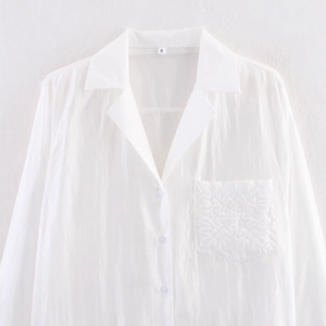 White embroidered shirt with notched lapel and intricate scrollwork detail on the pocket