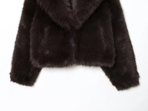 Detailed view of the dark brown faux fur texture and wide collar on a short winter coat