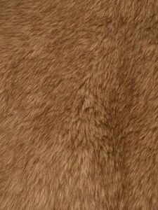 Macro shot of high-quality faux fur fabric with dense tan brown fibers and soft texture