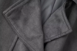 Close-up of the notch lapel and fine stitching on a dark grey suede texture coat