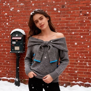 Grey off-the-shoulder knit sweater featuring a large bow with bright blue trim detail