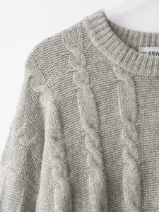 Détail du pull gris en maille torsadée avec col rond et finition de texture premium