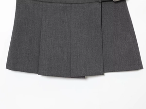 Détail macro du tissu plissé gris foncé avec boucle métallique sur une jupe courte