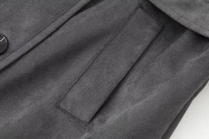 Detail of gray wool coat showing double-stitched pocket and black polished button