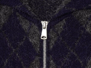 Detail of silver metal zipper on navy blue argyle knit cardigan with soft wool texture