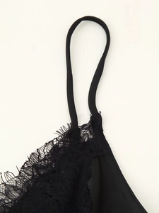 Macro shot of delicate eyelash lace trim and thin elastic straps on a black satin dress
