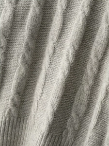 Détail macro de maille torsadée douce et ourlet côtelé sur un pull d'hiver gris