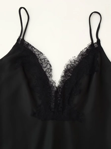 Close-up of fine eyelash lace trim on a black satin camisole with thin shoulder straps