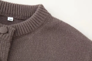 Détail du cardigan en tricot marron foncé montrant le col rond et la texture douce