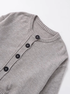 Detail of grey knit cardigan showing round neck ribbing and black button closure
