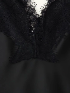 Close-up of intricate black eyelash lace detailing on a silky satin slip dress neckline