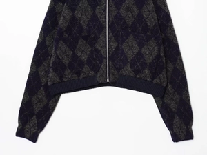 Detailed view of argyle knit cardigan with metal zipper and ribbed navy blue hemline
