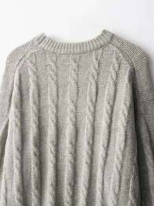 Gros plan sur la maille torsadée grise et l'encolure de ce pull d'hiver chaud et doux