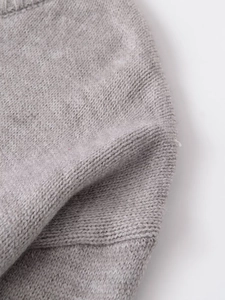 Close-up of soft gray knit fabric showing the detailed weave and hem of the sweater
