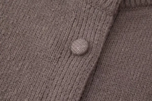 Vue macro détaillée de la texture du cardigan en maille marron et du bouton recouvert