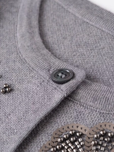 Close-up of dark grey knit cardigan featuring intricate hand-beaded metallic sequins