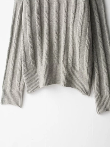 Détail de la texture d'un pull en maille torsadée grise avec finitions bord-côte