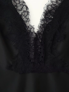 Detailed close-up of intricate black eyelash lace trim on a satin V-neck dress