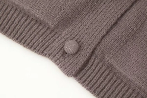 Détail du cardigan en maille avec boutons en tissu assortis et finition en côtes