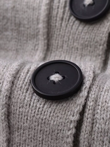 Close-up of light grey ribbed knit fabric featuring a large matte black button detail