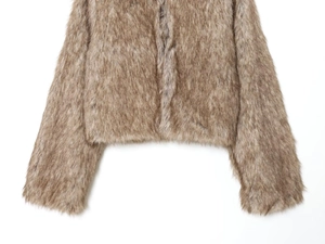 Detail shot of fluffy faux fur texture on the hem and cuff of this tan short jacket