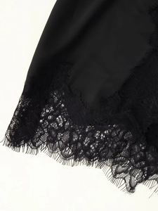 Detail of elegant black satin fabric with intricate eyelash lace trim along the hemline