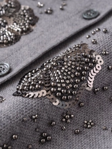 Detailed macro view of hand-beaded grey knit cardigan with floral sequins and buttons