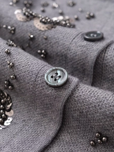 Close-up of grey beaded knit cardigan with dark sequins and resin buttons detail