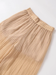 Detail of high-waist pleated wide-leg trousers in champagne with accordion texture