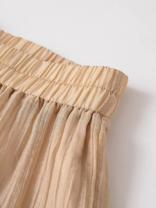 Close-up of elastic waistband and pleated texture on apricot translucent wide-leg pants