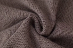 Détail macro du tricot taupe doux montrant les coutures fines et la texture de qualité