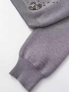 Close-up of grey knit cardigan featuring delicate hand-beaded sequins and ribbed cuffs