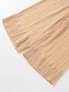 Detailed view of champagne pleated semi-transparent wide-leg trousers with fine hem stitching