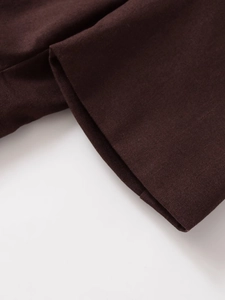 Macro shot of precision stitching and linen-blend fabric texture on a brown blazer sleeve