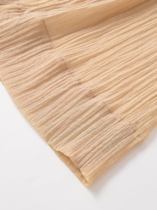 Detail view of light apricot crinkled fabric texture and neat stitching on leg hem