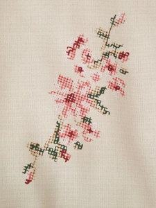 Detailed macro view of cross-stitch floral embroidery on beige linen cotton kimono fabric