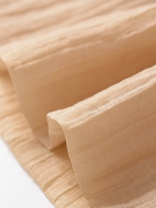 Macro detail of beige pleated fabric showing fine vertical texture and soft drape effect